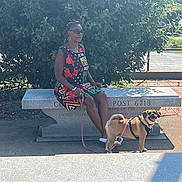 Roxxie is registered to the contest to win money with this photo: bench, black_dog, brown_dog, collar, dog, dogs, greenery, leash, memorial, outdoor, park, person, pets, portrait, sitting, standing, stone, sunlight, trees, woman