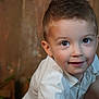 Côme a rejoint le concours — aidez-le/la à gagner de superbes lots ! child, boy, portrait, smile, curious, short_hair, white_shirt, indoor, wooden_background, face, happy, cute, young, closeup, person, casual_clothing, skin, expression, eyes, playful