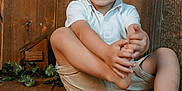 Côme participe au concours pour gagner de l'argent avec cette photo : child, boy, smiling, happy, sitting, wooden_floor, wooden_wall, shorts, white_shirt, barefoot, pine_cones, toys, dominoes, greenery, indoor, portrait, cute, playful, natural_light, casual