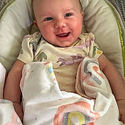 Alaina is registered to the contest to win money with this photo: baby, smiling, blanket, rainbow_pattern, cushion, infant, happy, face, clothing, cute, child, comfort, soft, lying_down, indoors, person, portrait, newborn, resting, cozy