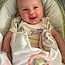 baby, blanket, child, clothing, comfort, cozy, cushion, cute, face, happy, indoors, infant, lying_down, newborn, person, portrait, rainbow_pattern, resting, smiling, soft