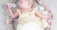 Justina joined the competition — help win amazing prizes! baby, child, cute, decorative_rope, flower_decor, headband, indoors, infant, knitted_clothing, newborn, peaceful, pink_flowers, portrait, resting, sleeping, small_feet, soft_blanket, white_flowers, wooden_swing, wrapped_in_blanket