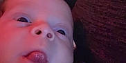 Logan Forrest is registered to the contest to win money with this photo: baby, face, hand, tongue, close_up, indoor, dim_light, person, infant, skin, expression, clothing, light, blur, background, portrait, young_child, human, head, cute