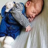 newborn, baby, sleeping, denim_overalls, striped_shirt, plush_toy, bunny, soft_blanket, infant, cute, peaceful, child, portrait, indoors, cozy, white_socks, resting, closeup, small_hands, toddler