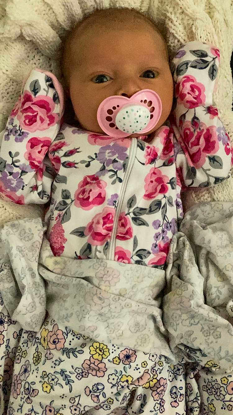 Eiley is registered to the contest to win money with this photo: baby, blanket, closeup, comfort, cute, face, floral, floral_pajamas, indoor, infant, knitted_blanket, lying_down, mittens, newborn, pacifier, pattern, person, resting, sleepwear, soft