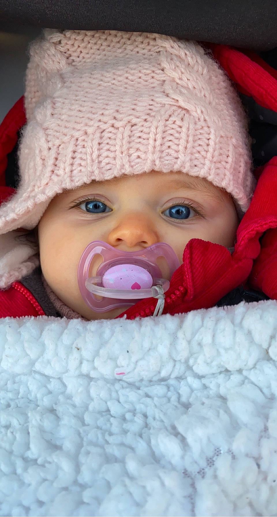 Ilona participe au concours pour gagner de l'argent avec cette photo : baby, baby_toddler_clothing, cap, cheek, chin, clothing, comfort, eye, face, head, headgear, headwear, iris, knit_cap, lip, mouth, nose, outerwear, person, pink