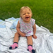 Delilah joined the competition — help win amazing prizes! baby, child, smiling, laughing, sitting, blanket, grass, outdoor, happy, cute, dress, socks, person, infant, nature, greenery, sunlight, playful, young, portrait