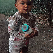 Charlette joined the competition — help win amazing prizes! toddler, child, outdoor, sidewalk, bottle, overalls, sneakers, face_stickers, crescent_moon, grass, bushes, buildings, trees, daylight, cute, standing, young_child, casual_clothing, playful, person