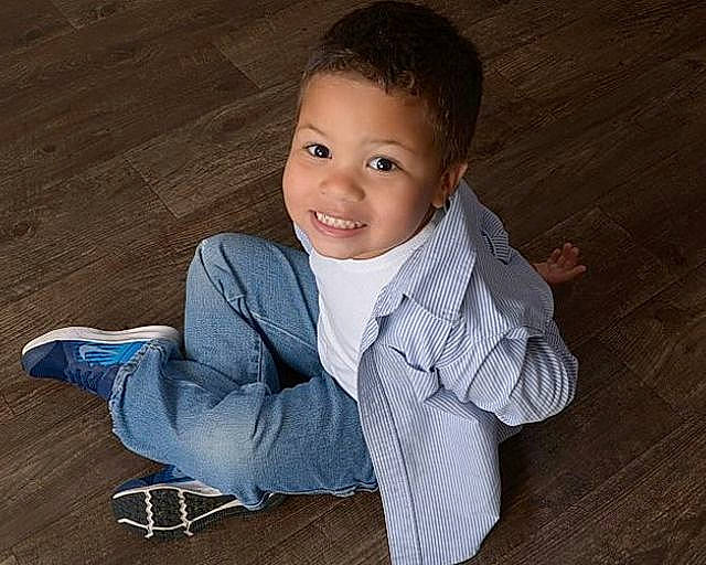 Breon is registered to the contest to win money with this photo: arm, cheek, child, child_model, chin, floor, flooring, hardwood, joy, lip, male, nose, outerwear, person, photography, sitting, skin, smile, standing, toddler
