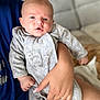 Simon participe au concours pour gagner de l'argent avec cette photo : baby, infant, person, hand, clothing, onesie, embroidery, couch, furniture, indoor, skin, face, expression, holding, blue_shirt, human, seated, comfort, closeup, newborn