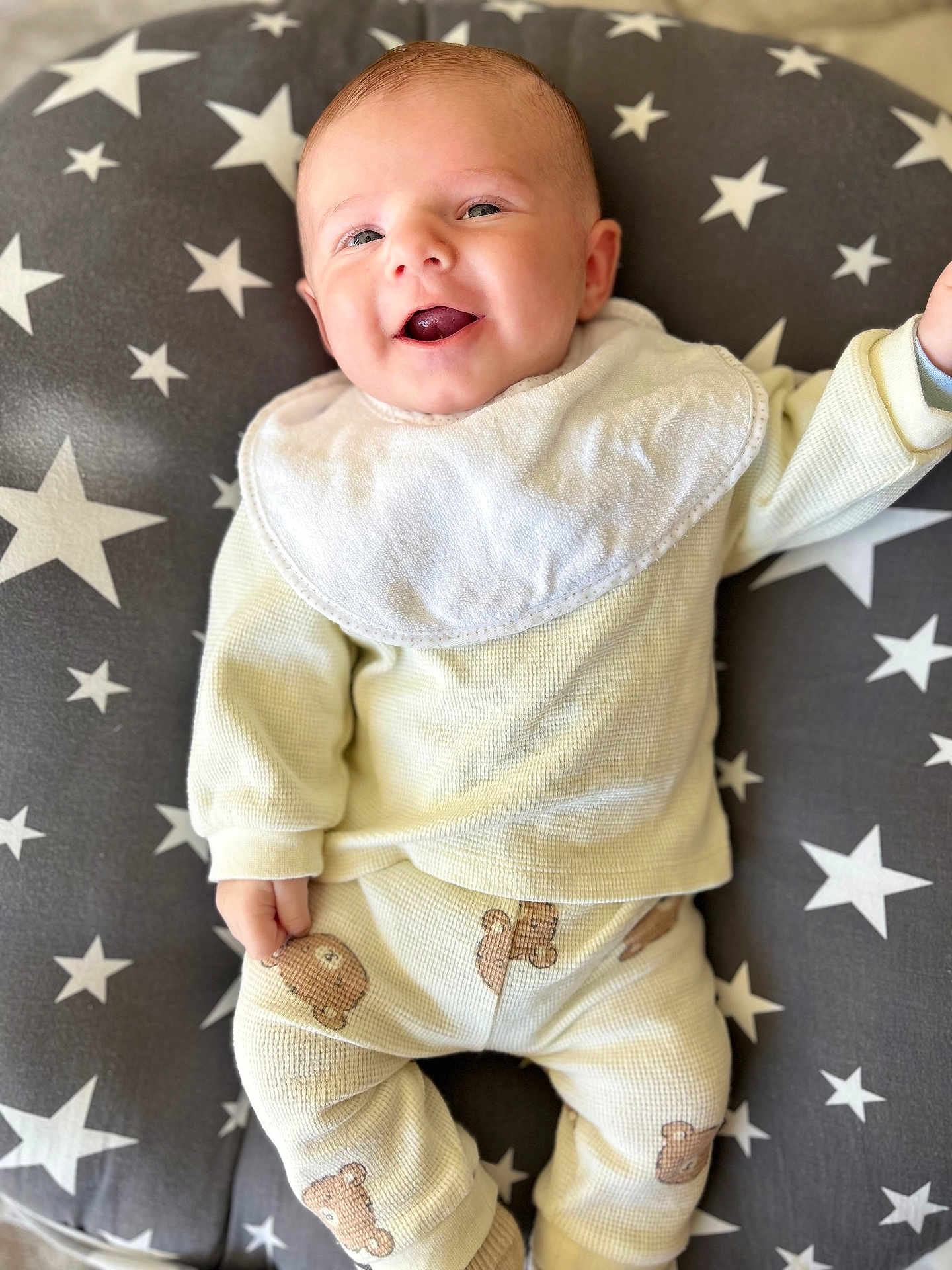 Simon participe au concours pour gagner de l'argent avec cette photo : baby, smiling, infant, pajamas, bib, face, person, lying_down, cushion, star_pattern, clothing, cute, happy, child, indoor, soft_texture, comfortable, adorable, portrait, young