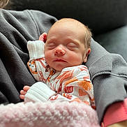 Oakley joined the competition — help win amazing prizes! baby, newborn, sleeping, blanket, onesie, patterned_clothing, person, arm, sleeve, cozy, soft_texture, indoor, closeup, face, peaceful, infant, rest, cuddle, comfort, warmth