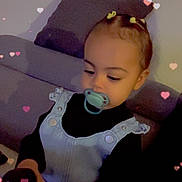 Cassie participe au concours pour gagner de l'argent avec cette photo : toddler, child, pacifier, remote_control, couch, pillow, hair_clips, hearts, indoors, black_clothing, denim_dress, sitting, cute, baby, hands, face, person, playing, relaxing, home