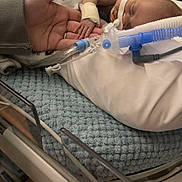 Johnathan is registered to the contest to win money with this photo: newborn, baby, hospital, incubator, medical_tubes, blanket, hand, adult_hand, infant, patient, healthcare, hospital_bed, medical_equipment, fragile, tiny, sleeping, care, love, tender_moment, person
