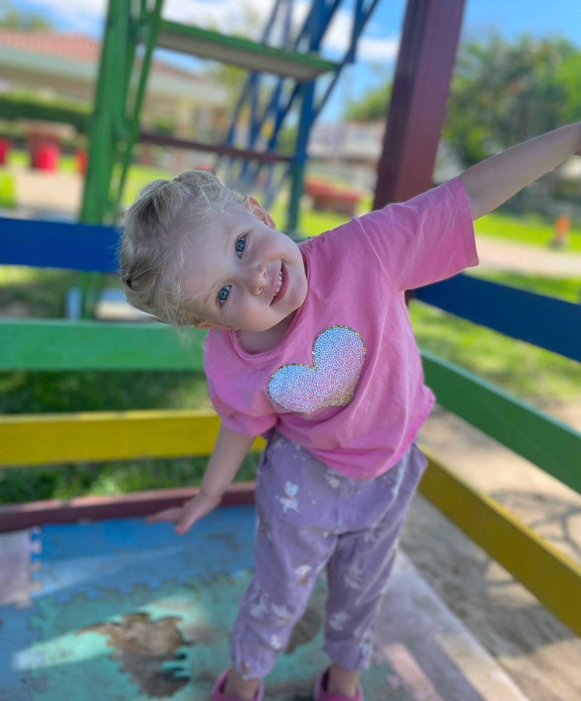 Samantha joined the competition — help win amazing prizes! baby, baby_toddler_clothing, child, city, fun, grass, happy, joy, leisure, magenta, outdoor_play_equipment, person, pink, play, playground, recreation, sitting, sky, smile, toddler