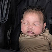 Jedi joined the competition — help win amazing prizes! baby, sleeping, stroller, child, infant, cute, face, curly_hair, closed_eyes, peaceful, beige_clothing, chubby_cheeks, portrait, resting, indoors, black_fabric, soft_lighting, young_child, cozy, toddler