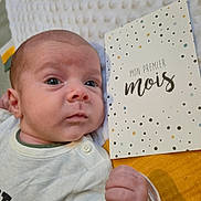 Esteban a rejoint le concours — aidez-le/la à gagner de superbes lots ! baby, infant, newborn, face, hand, blanket, card, text, clothing, laying_down, indoors, closeup, portrait, cute, young_child, skin, expression, soft_texture, neutral_colors, yellow