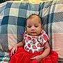 baby, bedroom, child, cute, fabric, home, indoor, infant, minnie_mouse, patterned_clothing, person, pillow, plaid_pattern, red_skirt, resting, sitting, smiling, soft_lighting, strawberry_print, toddler