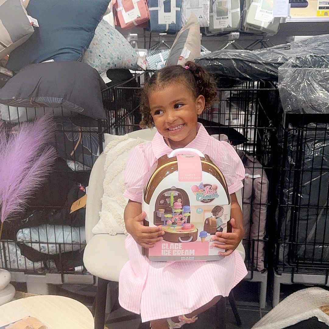 Rynade a rejoint le concours — aidez-le/la à gagner de superbes lots ! chair, child, cute, floor, footwear, girl, hair, happy, home_goods, ice_cream_set, indoor, person, pillow, pink_dress, rug, shopping, smile, store, table, toy