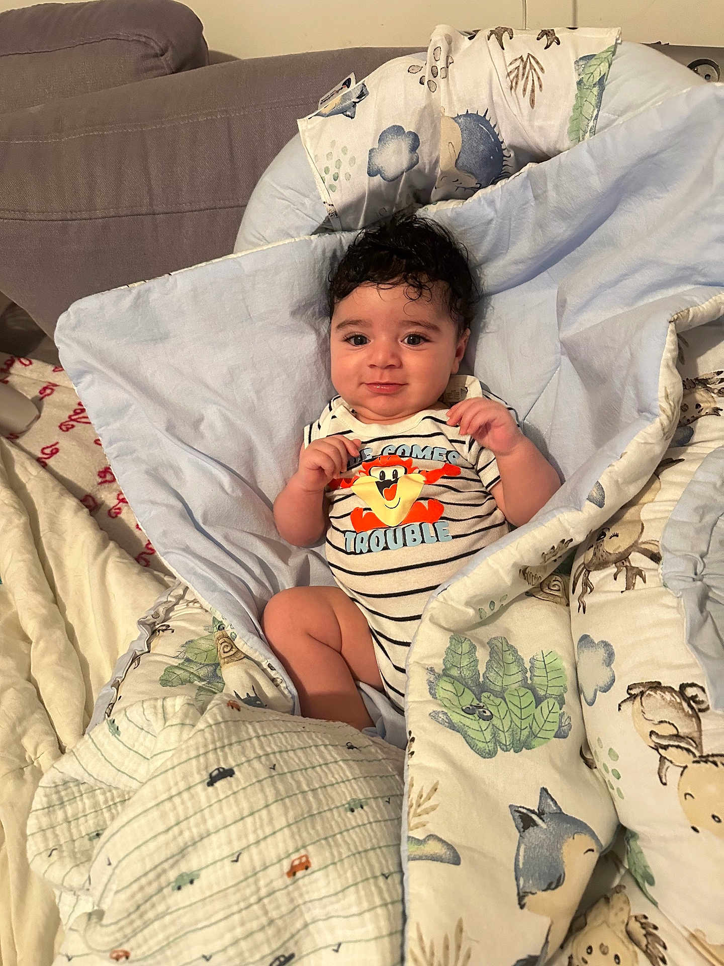 Ezekiel a rejoint le concours — aidez-le/la à gagner de superbes lots ! baby, child, blanket, bed, clothing, cute, face, funny_text, happy, indoor, infant, person, portrait, smile, striped_clothing, toddler, toy_pattern, warm, wrapped, young