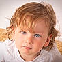 toddler, child, portrait, face, blue_eyes, curly_hair, white_shirt, close_up, expression, skin, person, young_child, indoor, looking_at_camera, cute, head_and_shoulders, natural_light, soft_background, texture, casual_clothing
