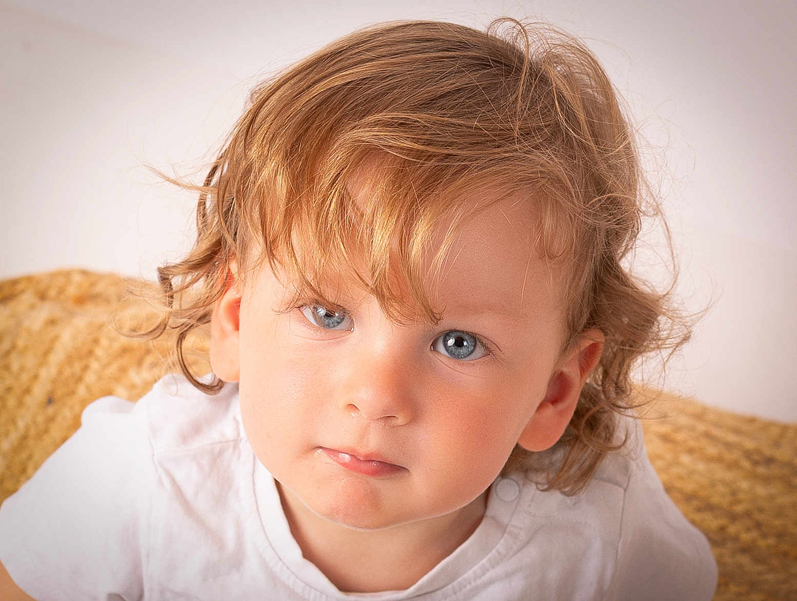 Léo participe au concours pour gagner de l'argent avec cette photo : toddler, child, portrait, face, blue_eyes, curly_hair, white_shirt, close_up, expression, skin, person, young_child, indoor, looking_at_camera, cute, head_and_shoulders, natural_light, soft_background, texture, casual_clothing