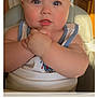 baby, child, blue_eyes, high_chair, hands, clasped_hands, face, skin, arm, kitchen, light, warm_light, indoor, person, cute, infant, tank_top, expression, closeup, portrait