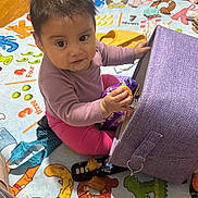 Ailany is registered to the contest to win money with this photo: baby, casual_clothing, child, colorful, curious, cushion, eyes, face, hardwood_floor, home, indoor, infant, play_mat, playtime, portrait, rug, sitting, smiling, snack_bag, toy