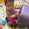 baby, casual_clothing, child, colorful, curious, cushion, eyes, face, hardwood_floor, home, indoor, infant, play_mat, playtime, portrait, rug, sitting, smiling, snack_bag, toy