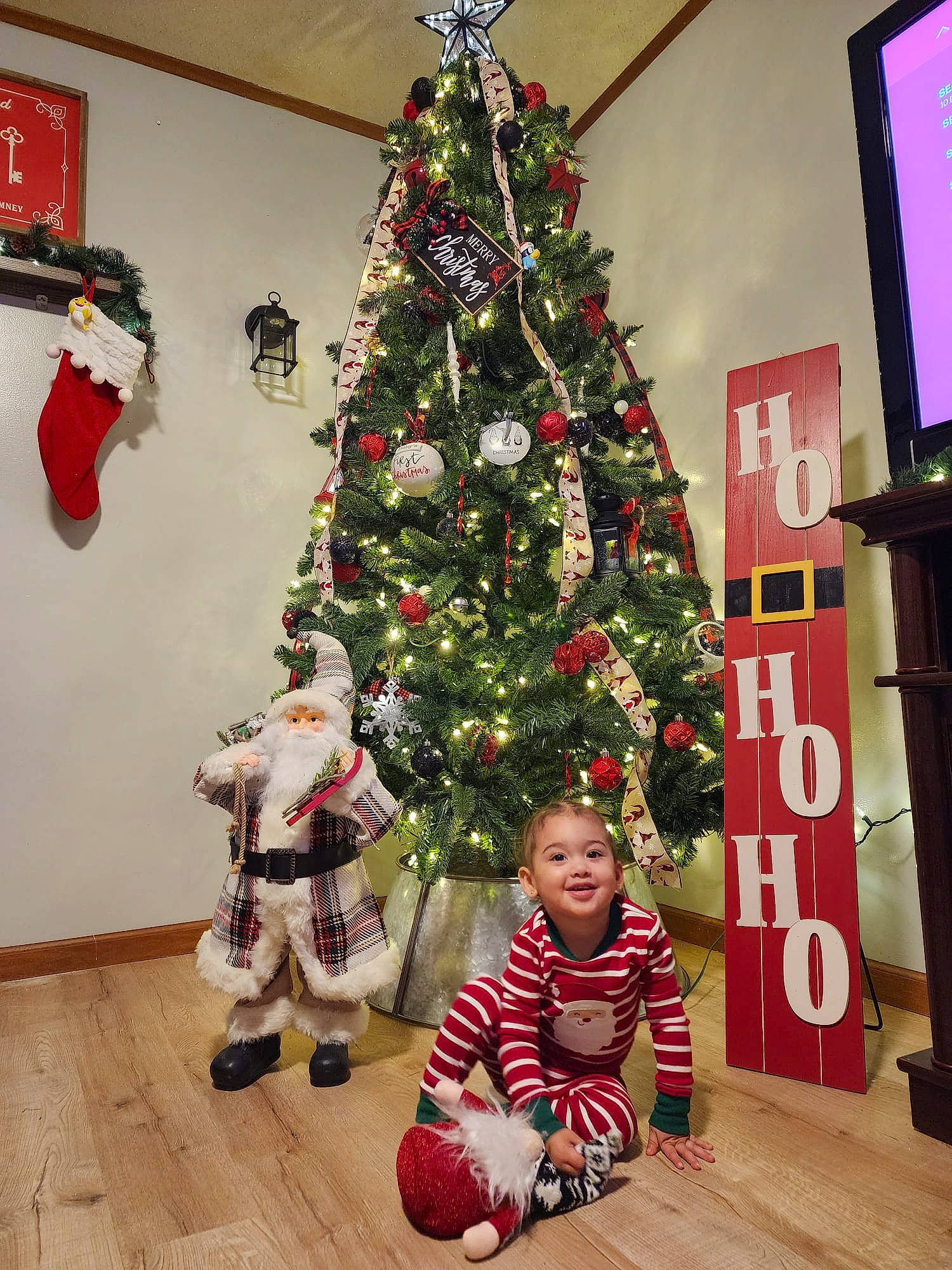 Kalani is registered to the contest to win money with this photo: christmas, christmas_decoration, christmas_ornament, christmas_tree, conifer, event, evergreen, flooring, holiday, holiday_ornament, joy, ornament, person, photograph, plant, red, snapshot, standing, toddler, tree