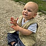 toddler, child, sitting, clapping, vest, white_shirt, pants, shoes, outdoor, gravel, happy, cute, smiling, baby, person, young_child, casual_clothing, natural_light, portrait, playful