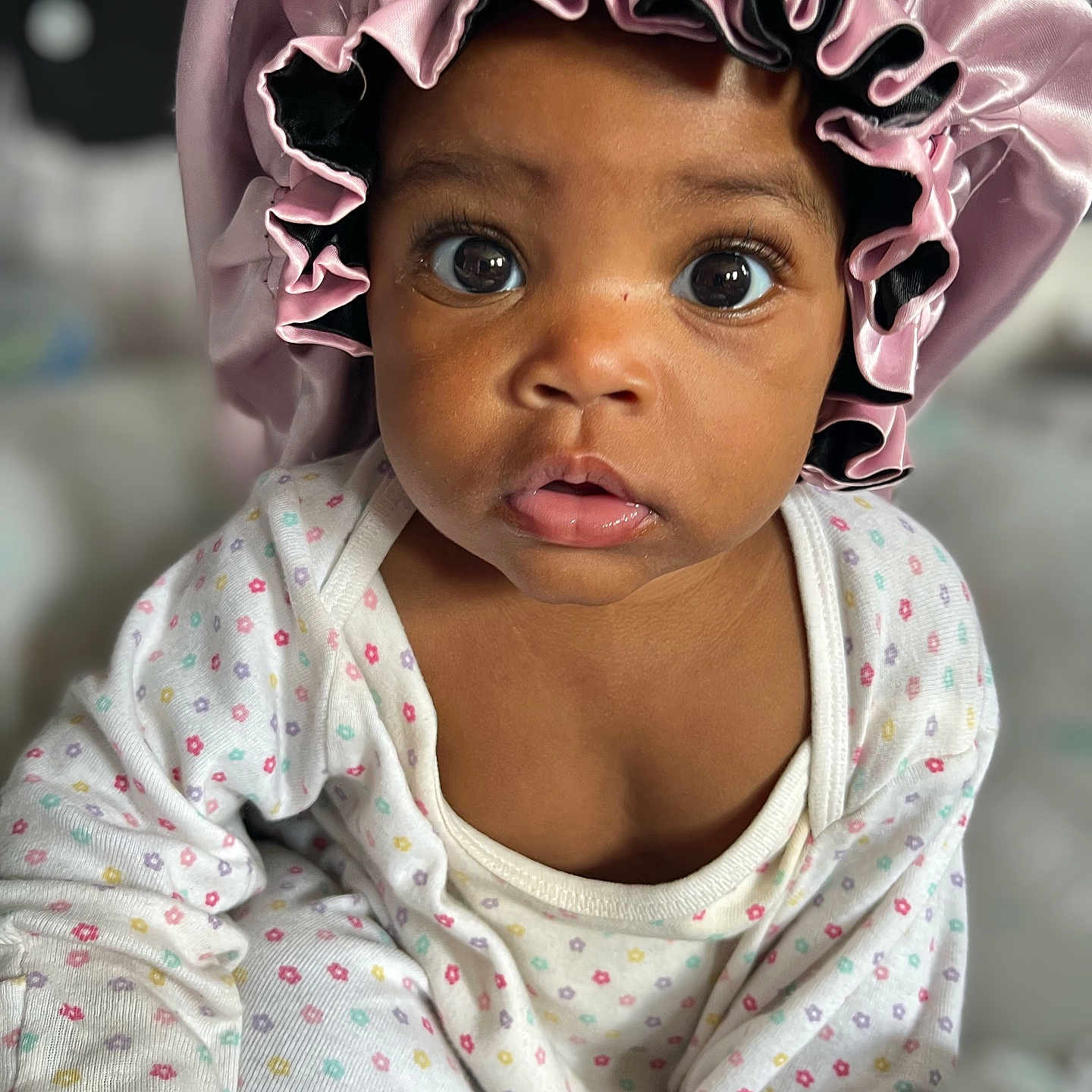 Samaria Nicole joined the competition — help win amazing prizes! baby, bonnet, child, close_up, curious, cute, expression, face, indoor, infant, pajamas, patterned_clothing, person, pink, portrait, sitting, skin, soft_light, wide_eyes, young