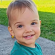 Jules a rejoint le concours — aidez-le/la à gagner de superbes lots ! toddler, child, smile, face, outdoor, grass, concrete, happy, young_child, person, casual_clothing, daylight, green, cute, portrait, eyes, head, skin, hair, nature