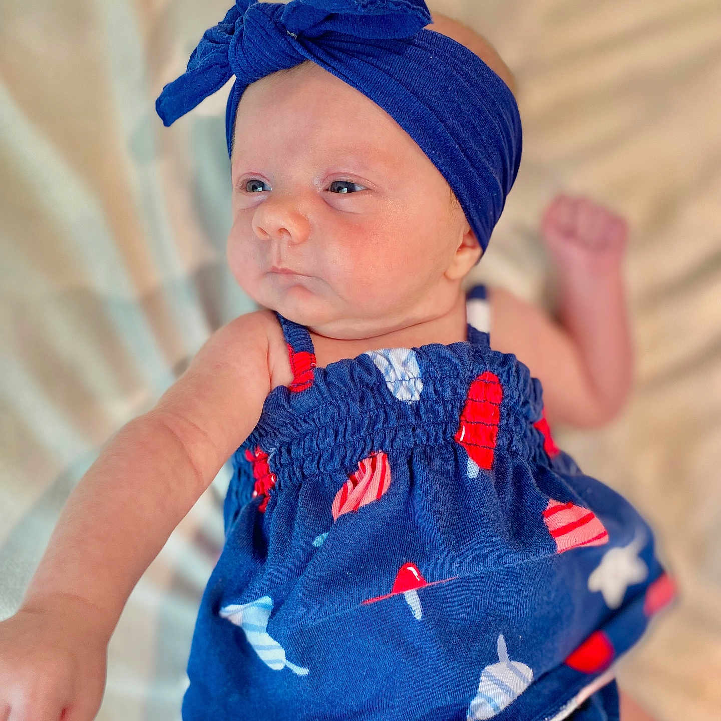 Brynlee joined the competition — help win amazing prizes! arm, baby, blanket, blue_dress, blue_headband, calm_expression, child, clothing, cute, face, headwear, indoors, infant, lying_down, popsicle_print, portrait, raised_fist, skin, soft_texture, young_child
