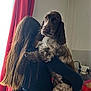 Daisy participe au concours pour gagner de l'argent avec cette photo : indoor, person, dog, holding, long_hair, black_top, blue_jeans, window, red_curtains, kitchen_sink, calm, brown_dog, white_dog, fur, home, appliance, light, curtains, back_view, casual