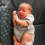 Samson is registered to the contest to win money with this photo: baby, child, cozy, curled_up, cute, face, feet, hands, indoor, infant, lying_down, newborn, onesie, patterned_background, peaceful, person, resting, sleeping, small, soft_focus