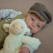 Arthur joined the competition — help win amazing prizes! baby, child, plush_toy, sheep, hat, knitted_clothing, couch, soft_toy, indoor, portrait, cute, infant, face, hand, cozy, relaxing, looking_at_camera, neutral_expression, fabric, comfort