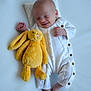 baby, infant, smiling, sleeping, plush_toy, yellow_bunny, white_onesie, soft_surface, cute, peaceful, newborn, child, cozy, relaxed, baby_feet, toy, cuddly, portrait, sleepwear, small_hands