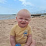 Caspian is registered to the contest to win money with this photo: baby, beach, sand, toy, smiling, child, water, sky, clouds, pier, outdoor, sunny, happy, sitting, casual_clothing, infant, cute, daytime, playful, nature
