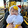 Caspian joined the competition — help win amazing prizes! baby, child, costume, chicken, fluffy, yellow, black_seat, hand, outdoor, sunset, vehicle, fire_extinguisher, smile, cute, person, seat, playful, happy, headwear, portrait