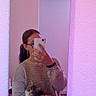 person, cat, kitten, mirror_selfie, smartphone, portrait, indoors, bathroom, reflection, holding, cuddling, sweater, skirt, earrings, ponytail, furniture, checkerboard_floor, pink_lighting, mirror, pet