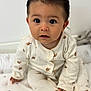 Giovanni a rejoint le concours — aidez-le/la à gagner de superbes lots ! baby, child, infant, pajamas, sitting, curious, indoors, patterned, cushion, closeup, portrait, cute, cozy, soft_lighting, expression, face, hands, footed_pajamas, young_child, white_background