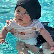 Giovanni participe au concours pour gagner de l'argent avec cette photo : baby, child, pool, water, swimming, infant, black_cap, tiger_print, cute, curious, sunlight, reflection, adult_hand, summer, outdoor, person, splash, skin, water_texture, support
