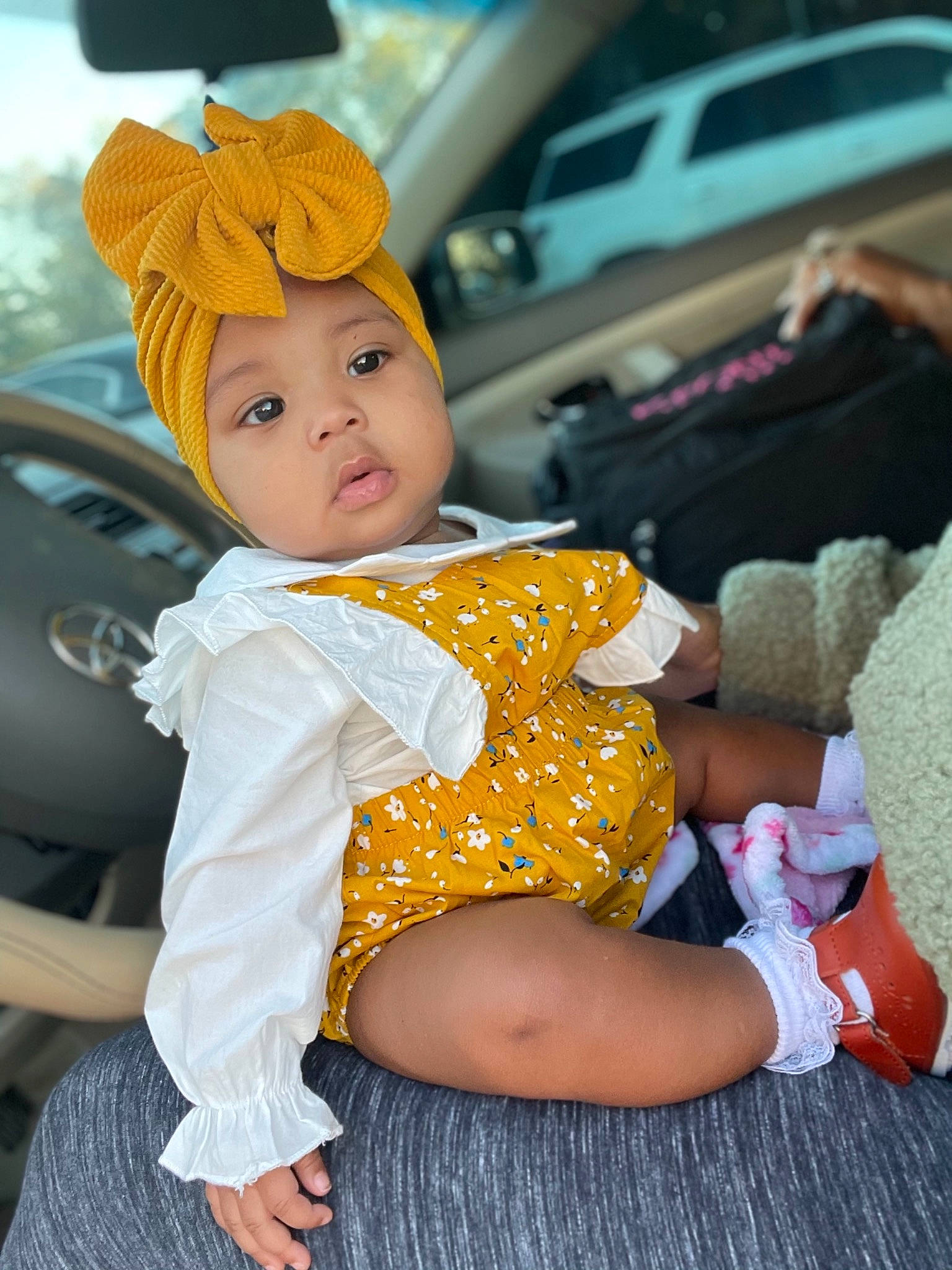 Keoni is registered to the contest to win money with this photo: baby, baby_toddler_clothing, bonnet, car_seat, costume_accessory, foot, headwear, lap, person, sock, toddler, turban, vehicle_door