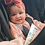 baby, car_seat, pink_clothing, headband, smile, child, infant, blanket, book, seatbelt, cute, face, portrait, indoors, happy, young_child, soft_texture, warm_colors, safety, cozy