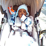 Moses joined the competition — help win amazing prizes! baby, child, stroller, carriage, canopy, blanket, earflap_hat, hat, mittens, snack_bag, chips, harness, buckle, seat, outdoor, sidewalk, pavement, portrait, cozy, relaxed