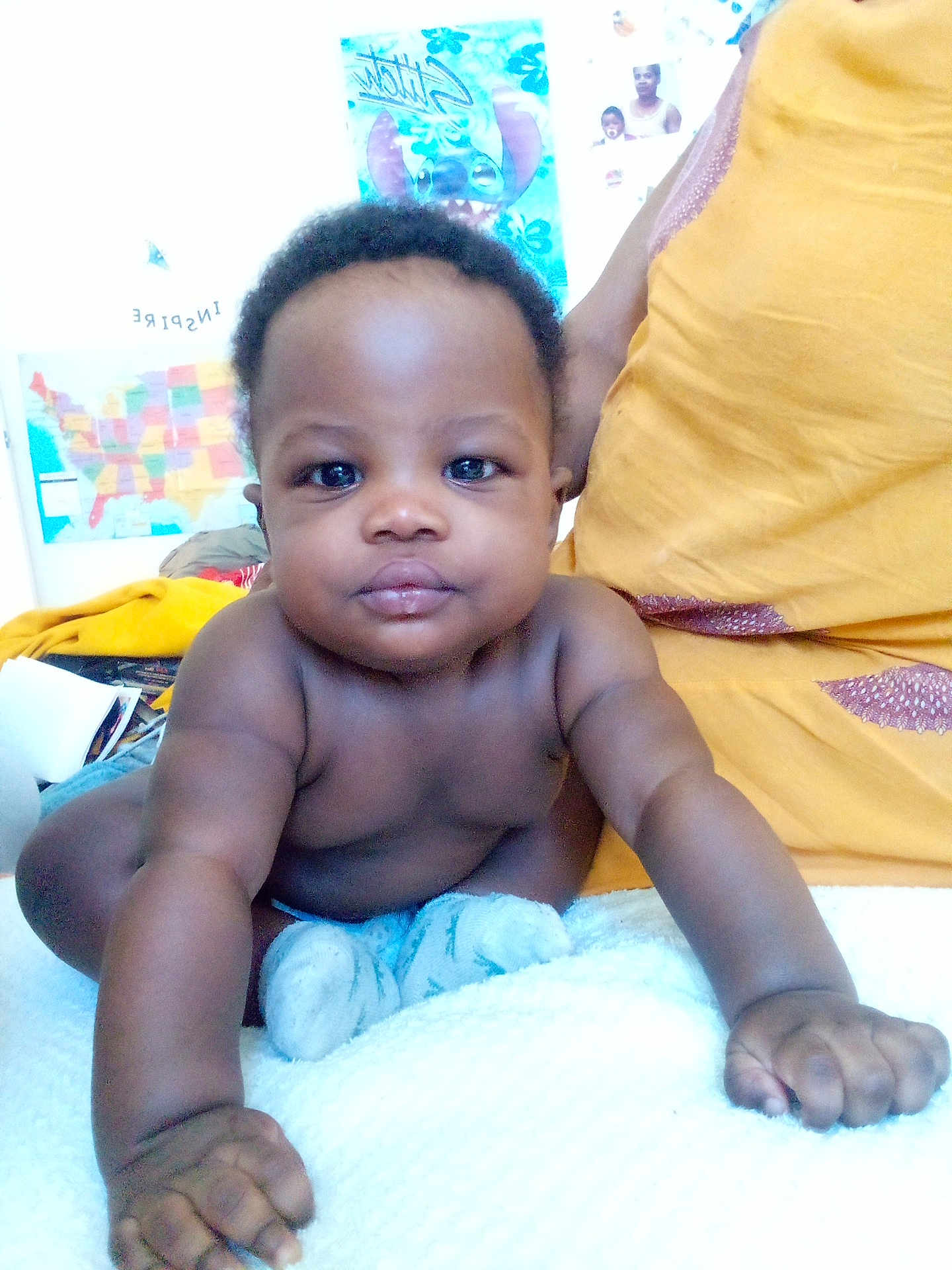 Moses is registered to the contest to win money with this photo: baby, child, infant, crawling, curious, skin, hand, footwear, blanket, adult, dress, indoor, poster, map, colorful, person, room, closeup, face, expression