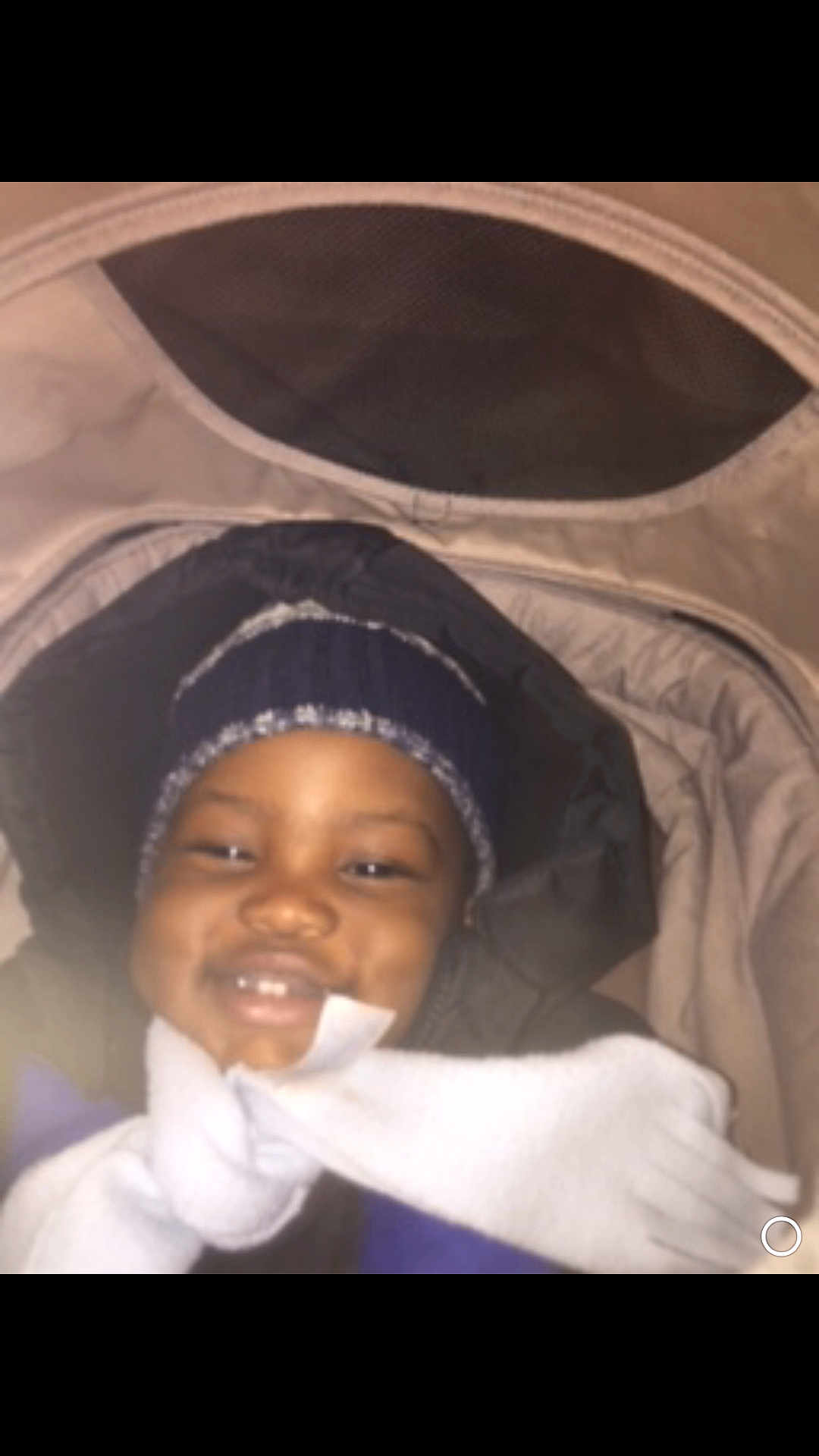 Moses is registered to the contest to win money with this photo: child, baby, infant, stroller, beanie, hat, scarf, jacket, coat, hood, blanket, smile, teeth, happy, portrait, close_up, indoor, flash, cozy, warm_clothing