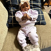 Avaia is registered to the contest to win money with this photo: baby, infant, child, couch, pillow, clothing, boots, headband, smile, face, indoors, cozy, fabric, furniture, person, apparel, comfortable, seated, cute, portrait