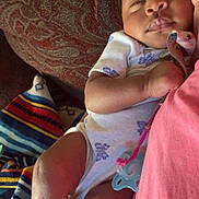 Denver Stallings is registered to the contest to win money with this photo: baby, sleeping, pacifier, blanket, cushion, patterned_fabric, infant, clothing, comfort, rest, colorful, soft, peaceful, person, indoors, closeup, skin, hand, foot, nap